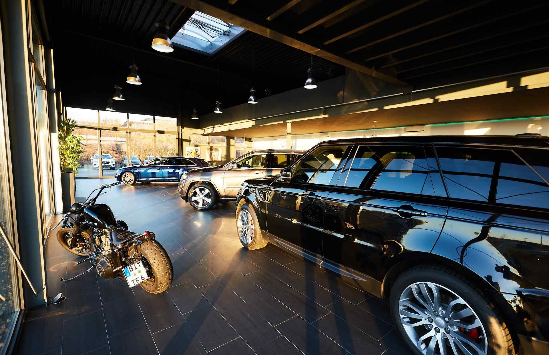Weiter Blick in den Ausstellungsraum mit Motorrad und Range Rover